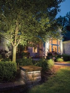 Stone work and landscaping brightly lit in front of a home