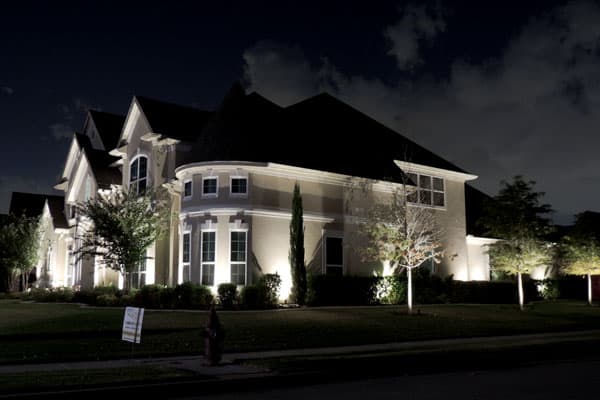 Bright lighting accents a corner house on a cloudy night
