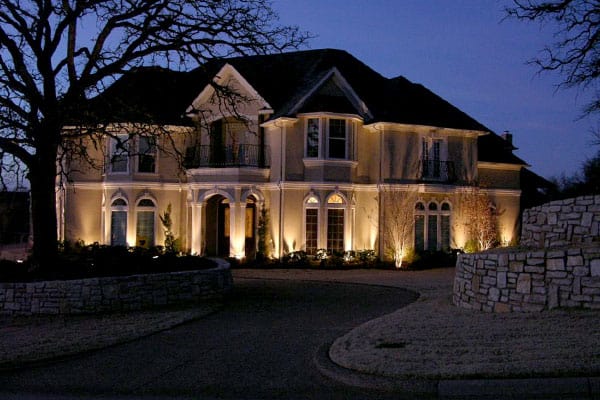 Two-story home lit up with security lighting at night