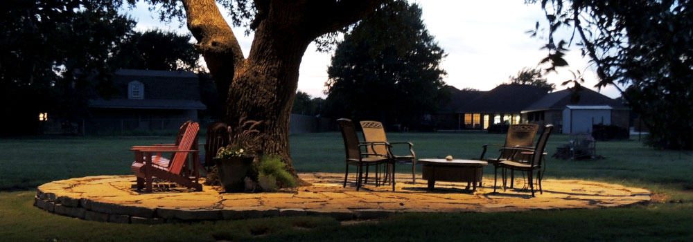 LED Lighting on a tree and patio furniture on stone slab in the backyard