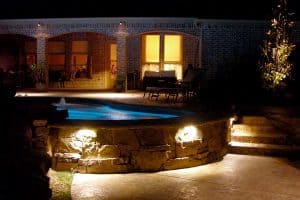 A backyard pool lit up and ready to be enjoyed on a beautiful night