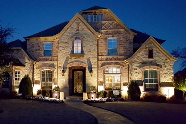 A Dallas Ft Worth area home is illuminated at night by outdoor lighting